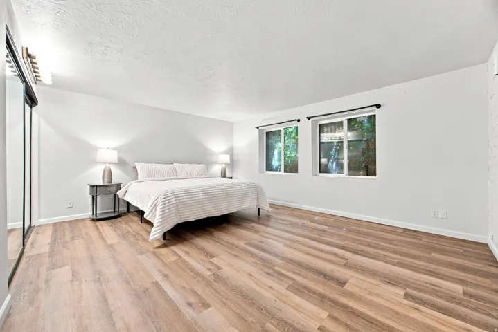 Wood-finish flooring, white walls, and a white ceiling create a neutral palette