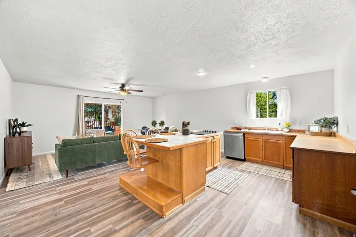 Open-concept living space featuring wood-finish flooring, a kitchen island with seating, wood cabinetry, and a sliding glass door to the exterior