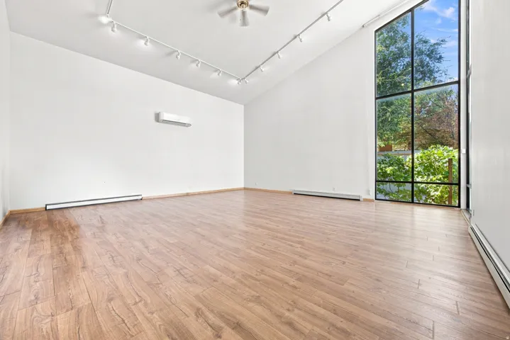 Vaulted ceiling, wood-finish flooring, full-height window, ceiling fan, track lighting