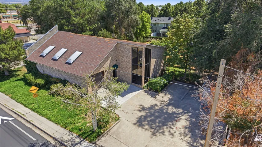 Brick exterior, multi-pane skylights, mature landscaping, paved parking area, and multi-story window feature
