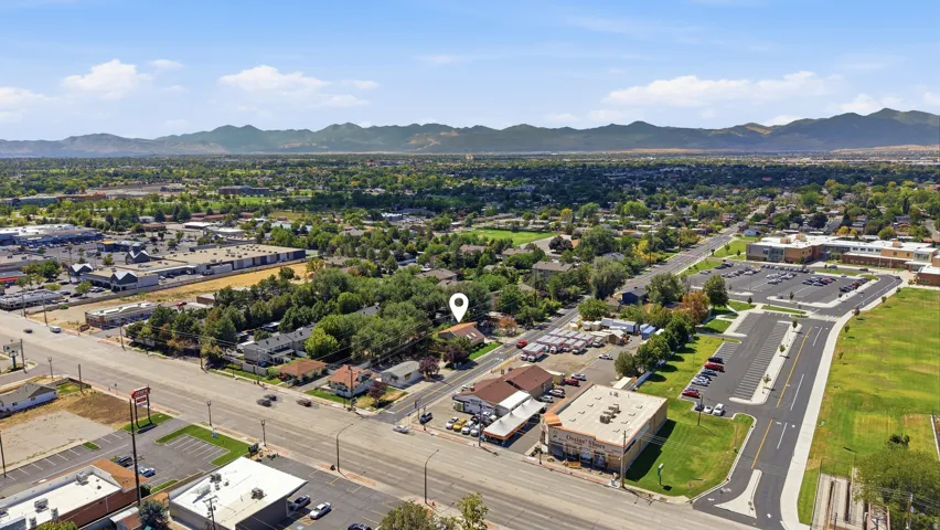 Aerial perspective highlighting a tree-lined residential area with proximity to commercial establishments and mountain scenery