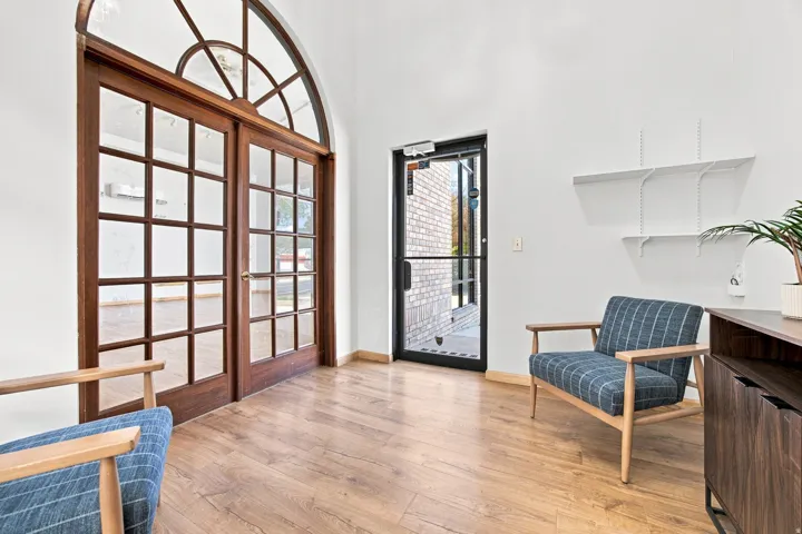 Arched transom window and double glass doors, wood-finish flooring, built-in shelving, and white walls
