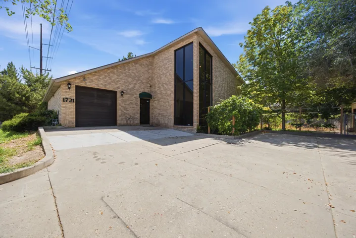 Brick exterior with a peaked roofline, expansive front windows, and an integrated garage