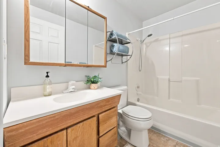 Bathroom with a wood-finish vanity, integrated sink, and a mirrored medicine cabinet