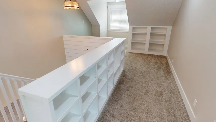 Built-in shelving, recessed built-in shelving, shiplap accent wall, overhead light fixture, and window with blinds