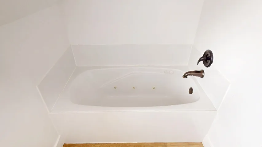 Jetted soaking tub with a dark bronze faucet and wall-mounted shower head