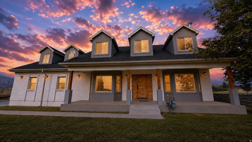 This is an Ai enhanced Photo. White brick exterior with gray accents, wood-finish front door, front porch with wood-wrapped columns, and multiple dormer windows