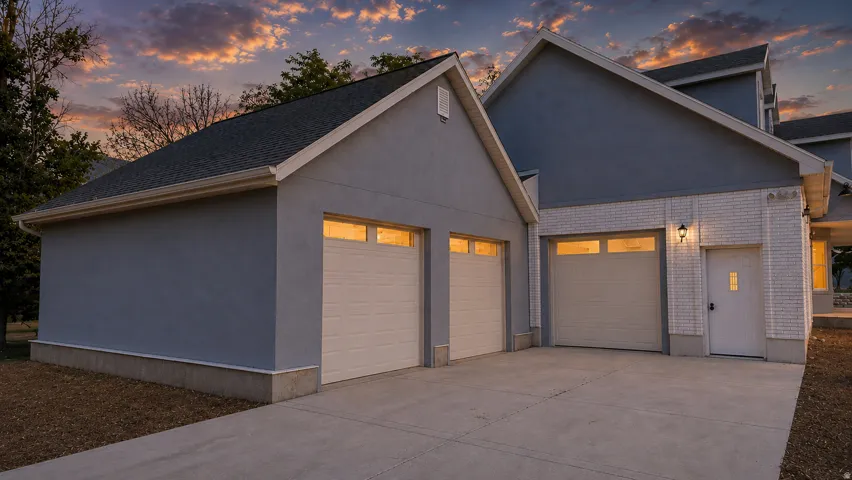 This is an Ai enhanced Photo. Concrete driveway leading to a two-car garage with overhead doors and transom windows