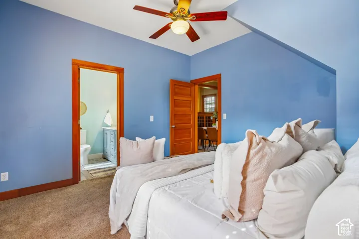 Angled ceiling with a ceiling fan, wood-trim doorways, and wall-to-wall carpeting