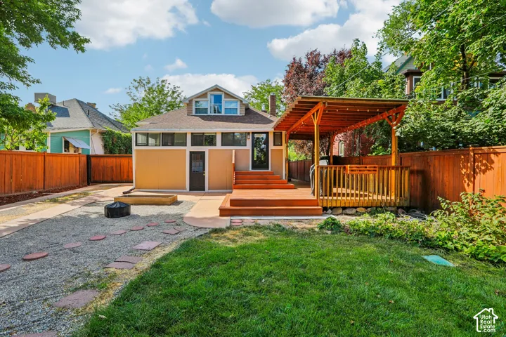 Expansive backyard featuring a covered wood deck, gravel path with stepping stones, and a manicured lawn