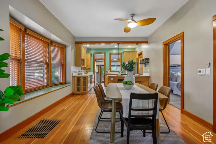 Hardwood flooring, wood trim, bay window, built-in cabinetry, and a ceiling fan with integrated lighting