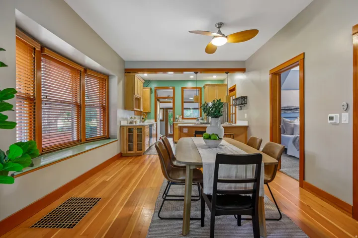 Hardwood flooring, wood trim, bay window, built-in cabinetry, and a ceiling fan with integrated lighting