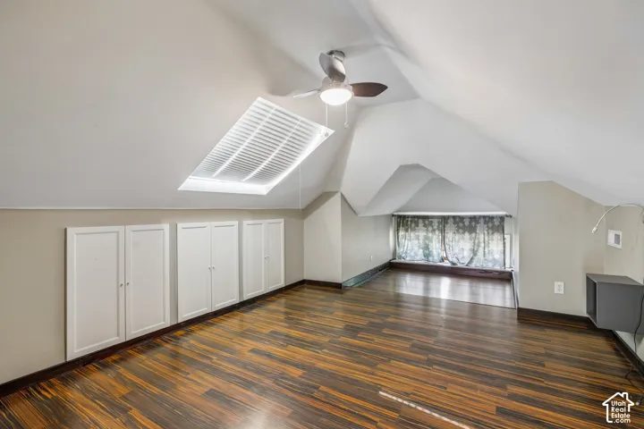 Wood-finish flooring, built-in white cabinetry, skylight, and a ceiling fan with integrated lighting