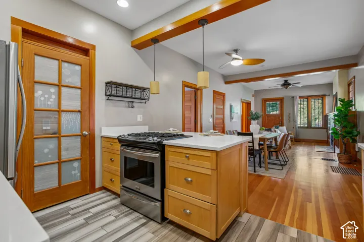 Kitchen island with integrated stainless steel range, wood-finish cabinetry, and solid surface countertops