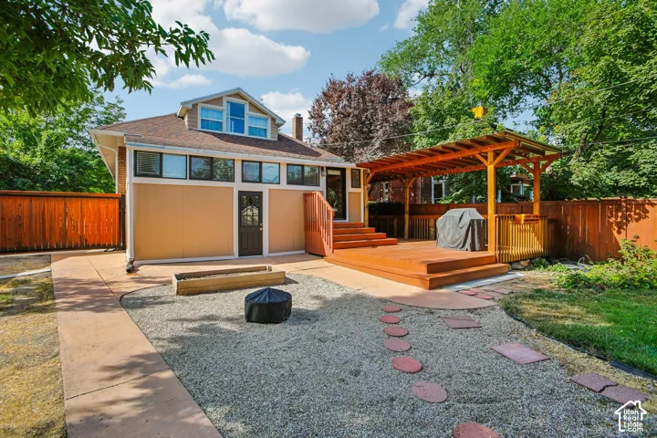Expansive backyard featuring a gravel patio, concrete pathway, wood deck, and an attached wood pergola