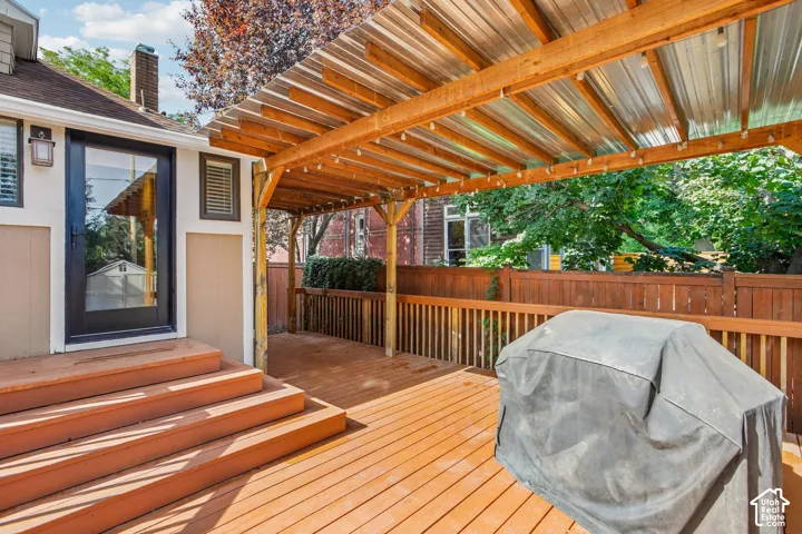 Wood deck with a clear corrugated roof covering, wooden railings, and a solid exterior door