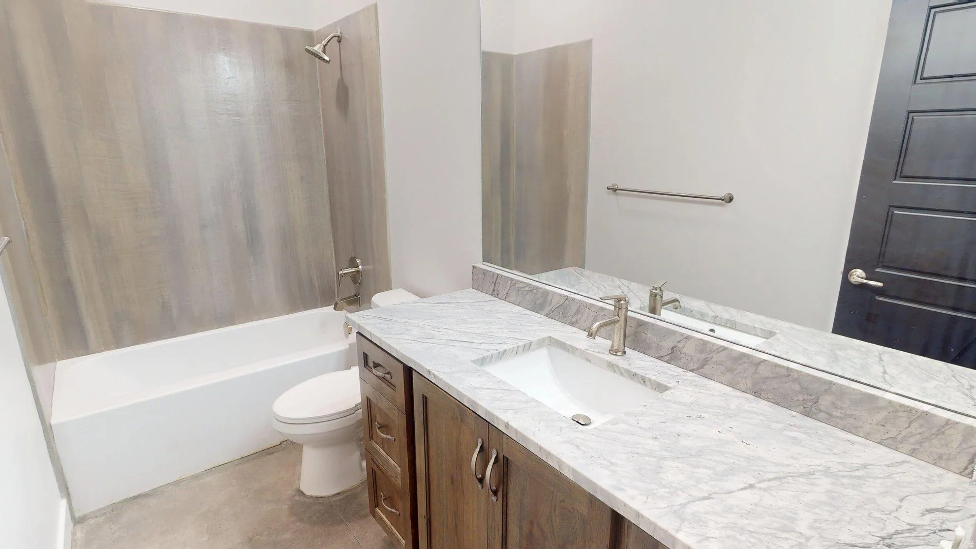 Bathroom featuring a spacious vanity with stone-finish countertop, undermount sink, and wood-finish cabinetry