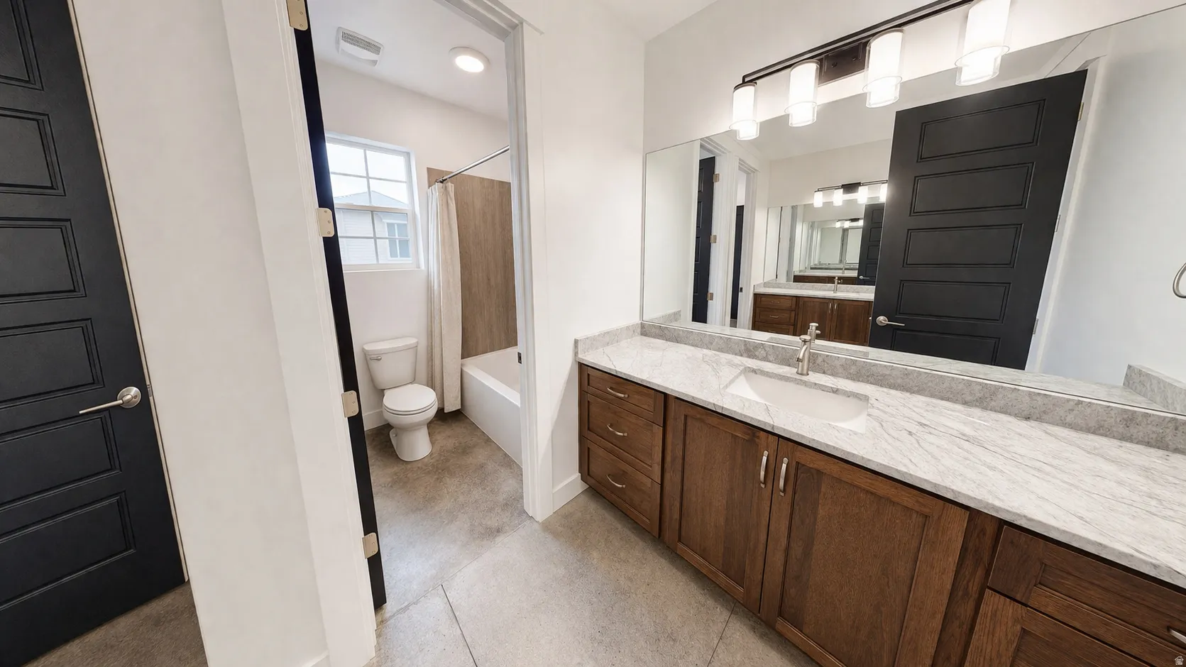 Dual-sink vanity with wood-finish cabinetry, light-toned countertop, and undermount sinks