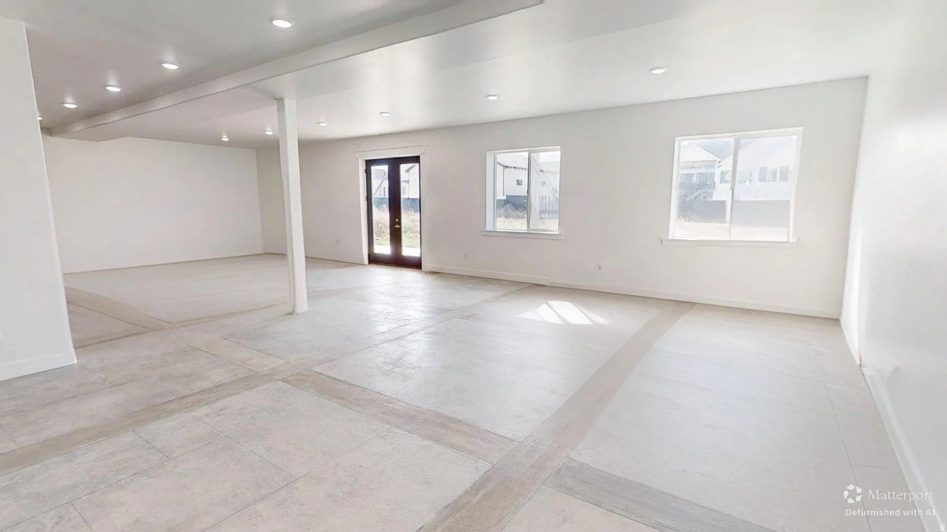Spacious interior featuring light-colored flooring, white walls, recessed lighting, and multiple windows