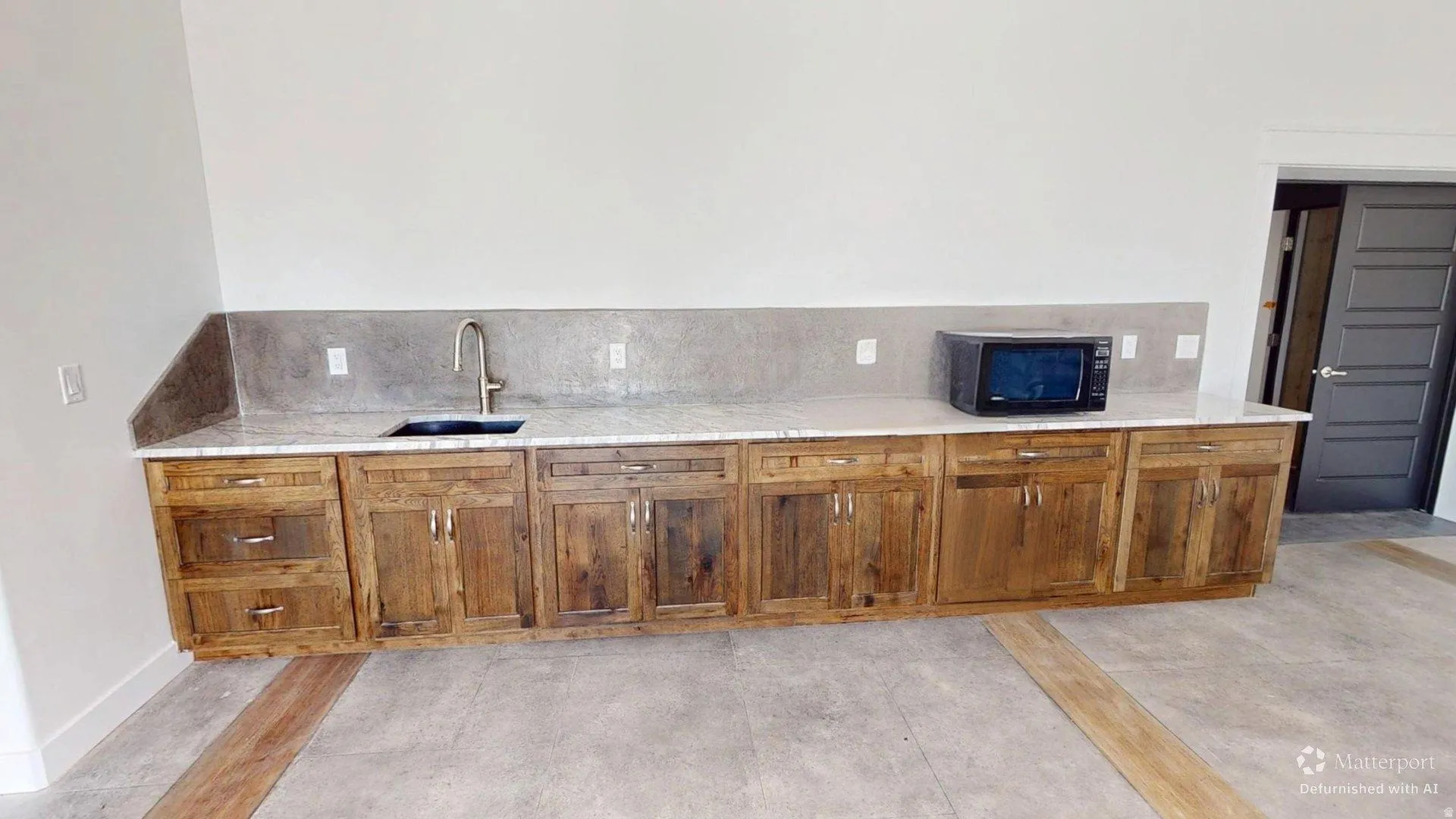 Custom wood cabinetry with extensive storage, light-toned countertop, and undermount sink with a gooseneck faucet