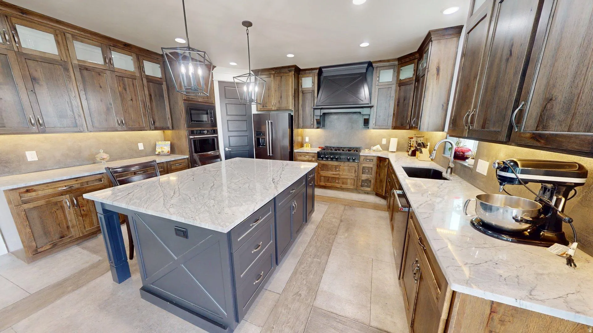 Kitchen featuring a large central island with a light-toned countertop, wood-finish cabinetry, built-in double ovens, and recessed lighting