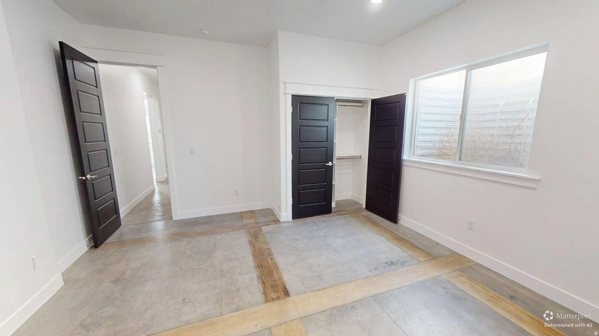 Polished concrete flooring, recessed lighting, white walls, dark paneled doors, and a built-in closet with shelving