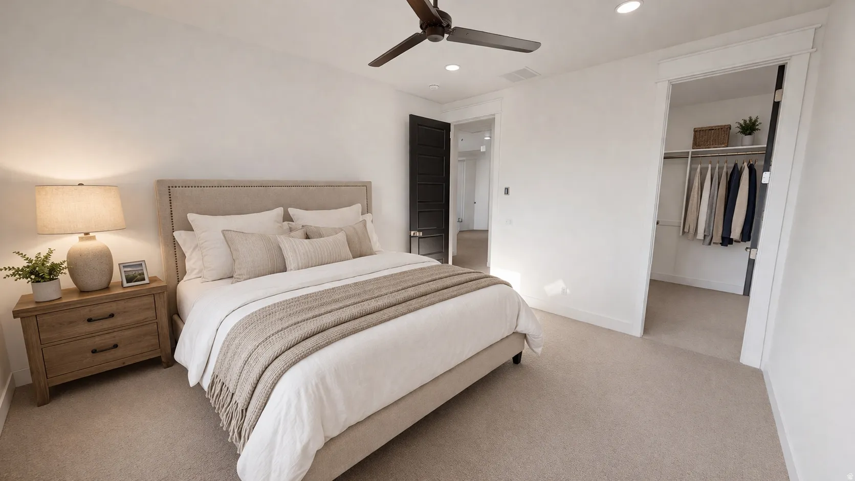 This is an Ai enhanced Photo. Carpeted flooring complemented by white walls, a dark ceiling fan, recessed lighting, and a walk-in closet with built-in shelving