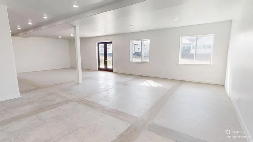 Spacious interior featuring light-colored flooring, white walls, recessed lighting, and multiple windows