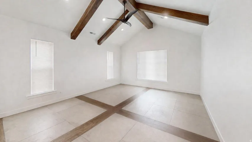 Vaulted ceiling with exposed wood beams and recessed lighting