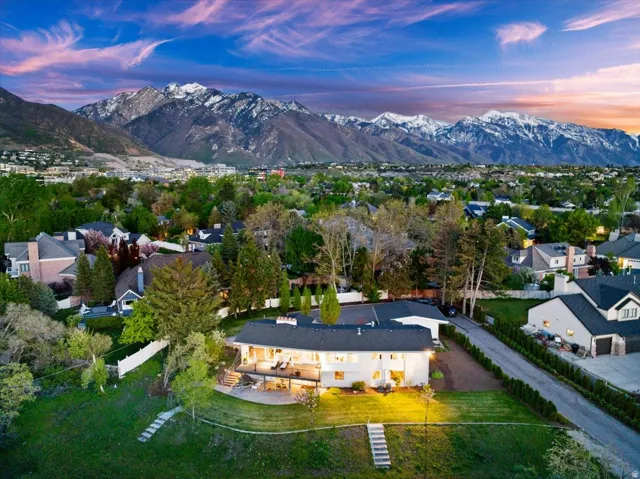 Twilight aerial showcasing the home’s secluded Holladay setting with incredible Wasatch Mountain views.