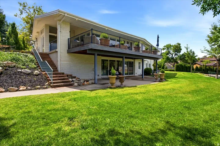 Rear exterior showcasing the walkout lower level, expansive lawn, upper deck, and covered patio.