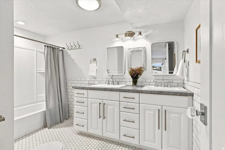 Updated lower-level bathroom with dual vanity, white cabinetry, and subway tile finishes.