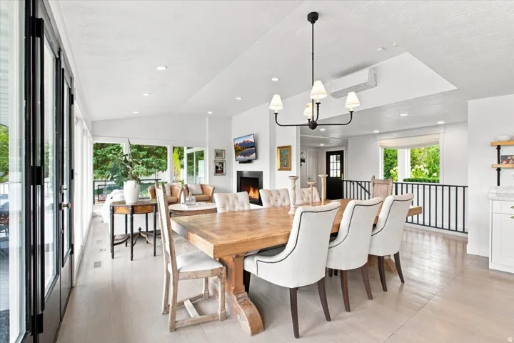 Open-concept dining and living space with hardwood floors, vaulted ceilings, and direct access to the outdoor deck.