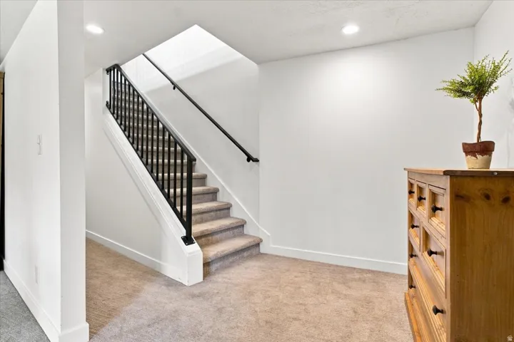 Stairway to the finished walkout lower level with black metal railing and abundant natural light.