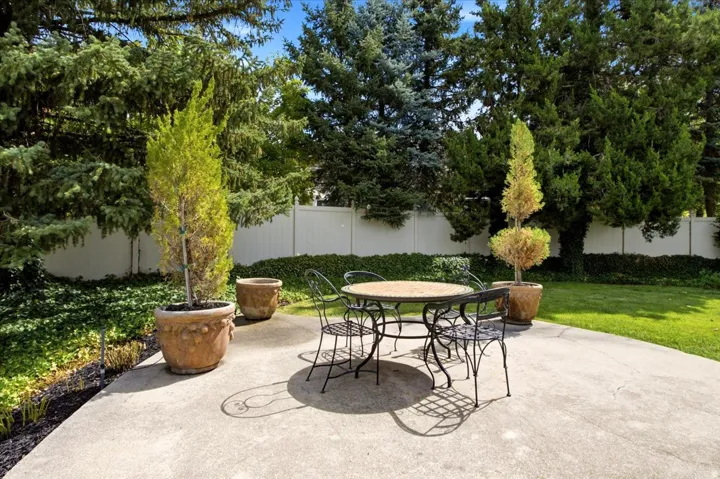 Private courtyard-style patio surrounded by mature landscaping, ideal for outdoor dining and entertaining.
