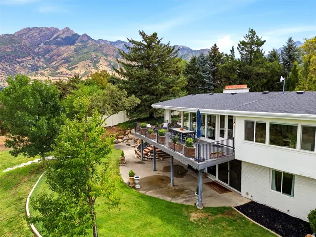 Elevated rear view showcasing the Trex deck, covered lower patio, walkout basement, and mature mountain setting.