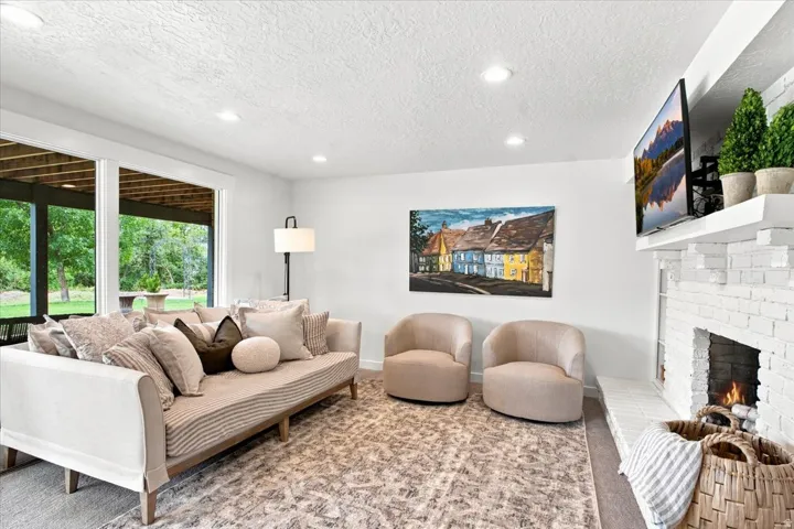 Finished lower-level family room with white brick fireplace, recessed lighting, and generous gathering space.