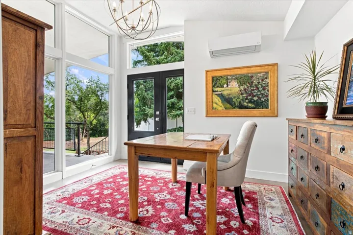Light-filled main-level home office with French doors and views of the mature landscaping.