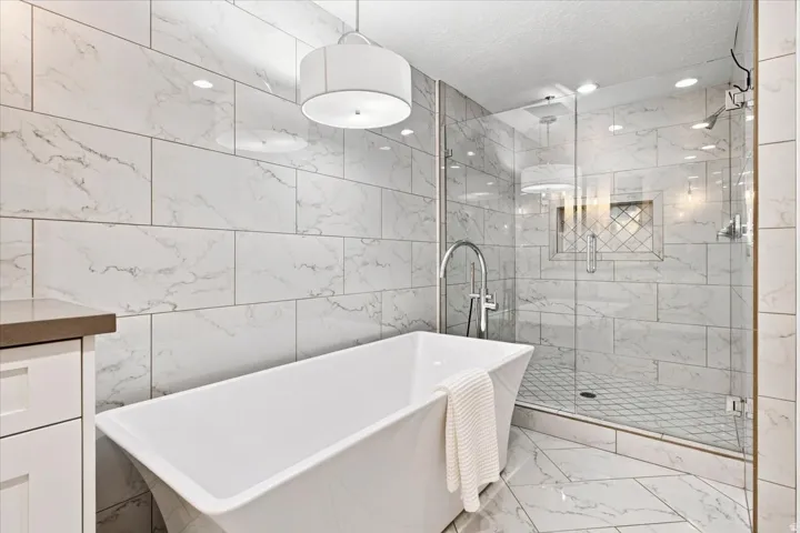 Spa-inspired primary bathroom with freestanding soaking tub, oversized glass shower, and designer finishes.