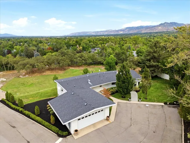 Elevated aerial showcasing the .54-acre residence, expansive lawn, mature trees, and surrounding Holladay setting.