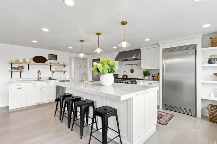 Updated gourmet kitchen with oversized island, quartzite countertops, built-in refrigerator, and stainless steel appliances.