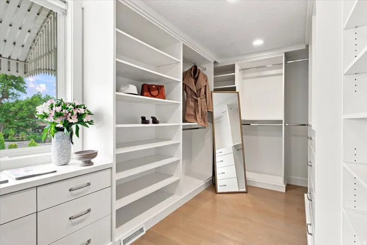 Custom walk-in primary closet with built-in shelving, drawers, and abundant storage.