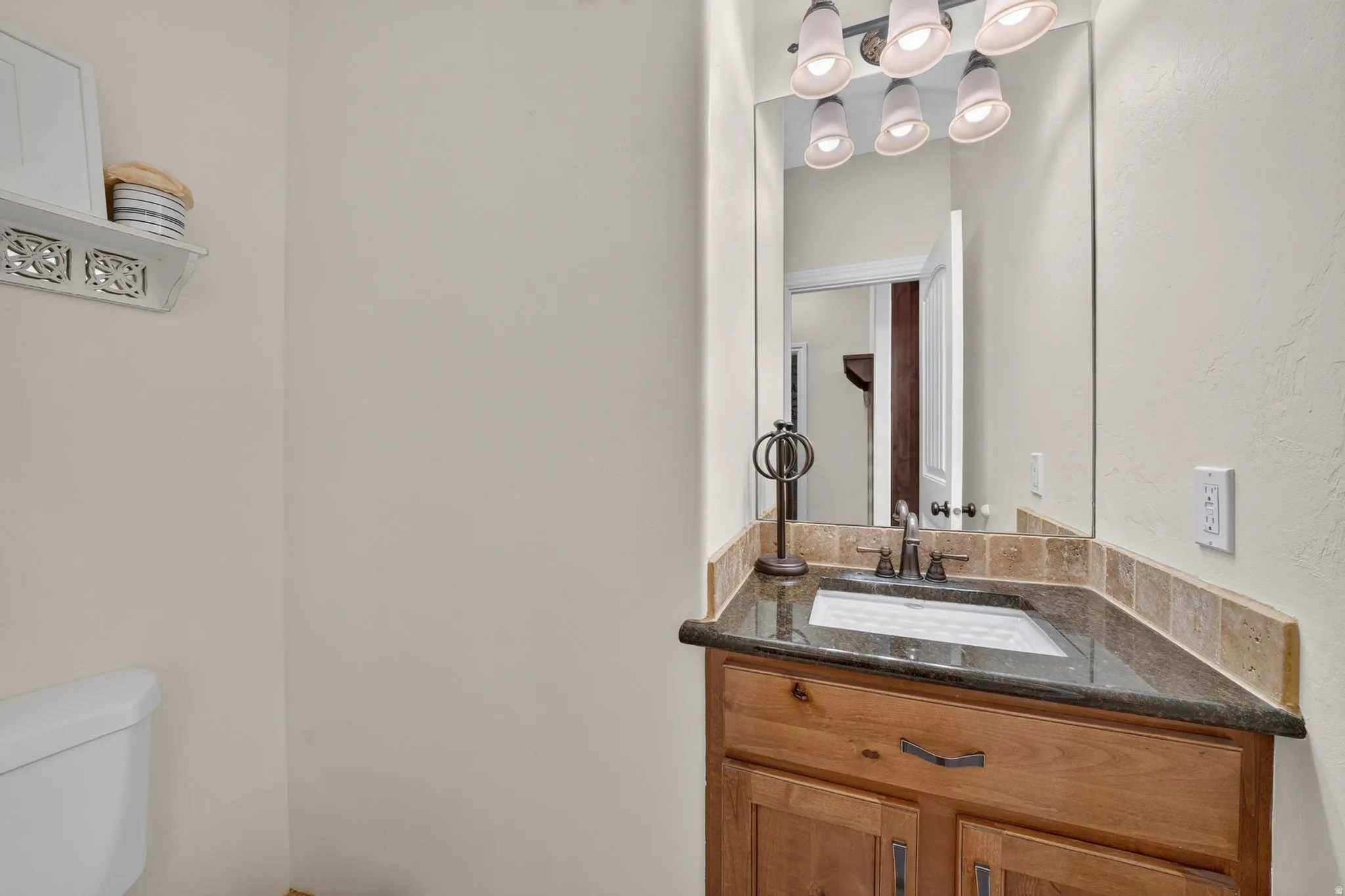 Corner vanity with a dark countertop and undermount sink