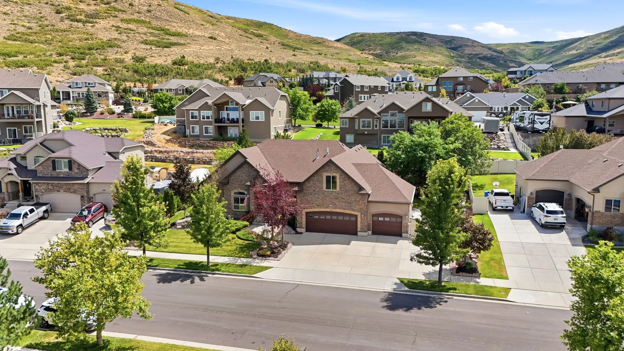 Brick and stucco facade home with an attached three-car garage, concrete driveway, and mature landscaping