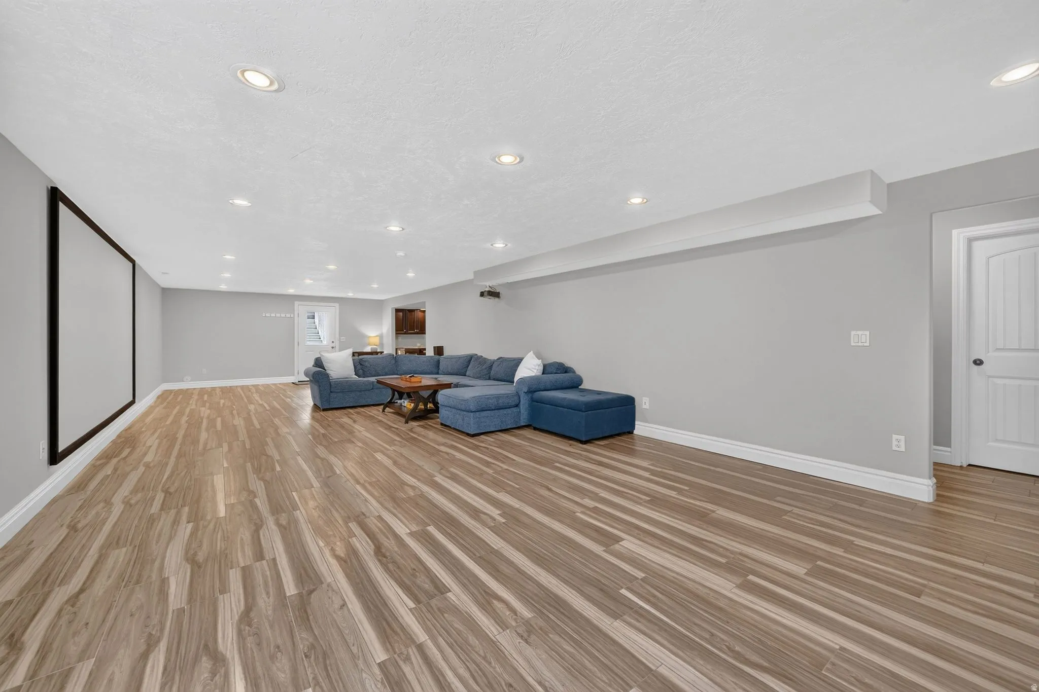 Spacious room with wood-finish flooring, recessed lighting, and a projection screen