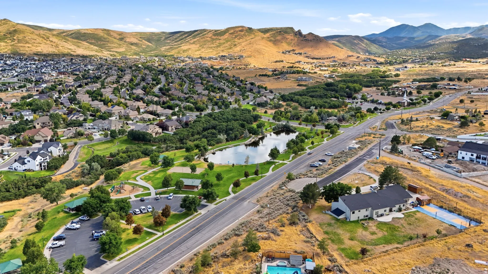 Expansive community featuring a large pond, recreational park areas, and mountain backdrops