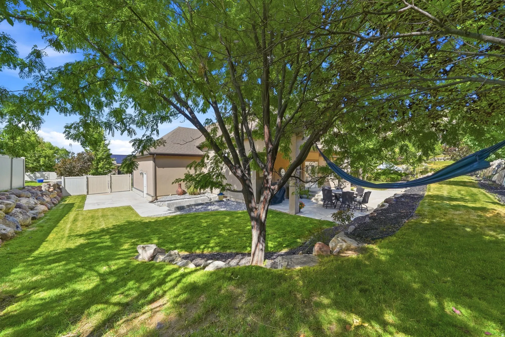 Expansive lawn with mature trees and a paved patio area