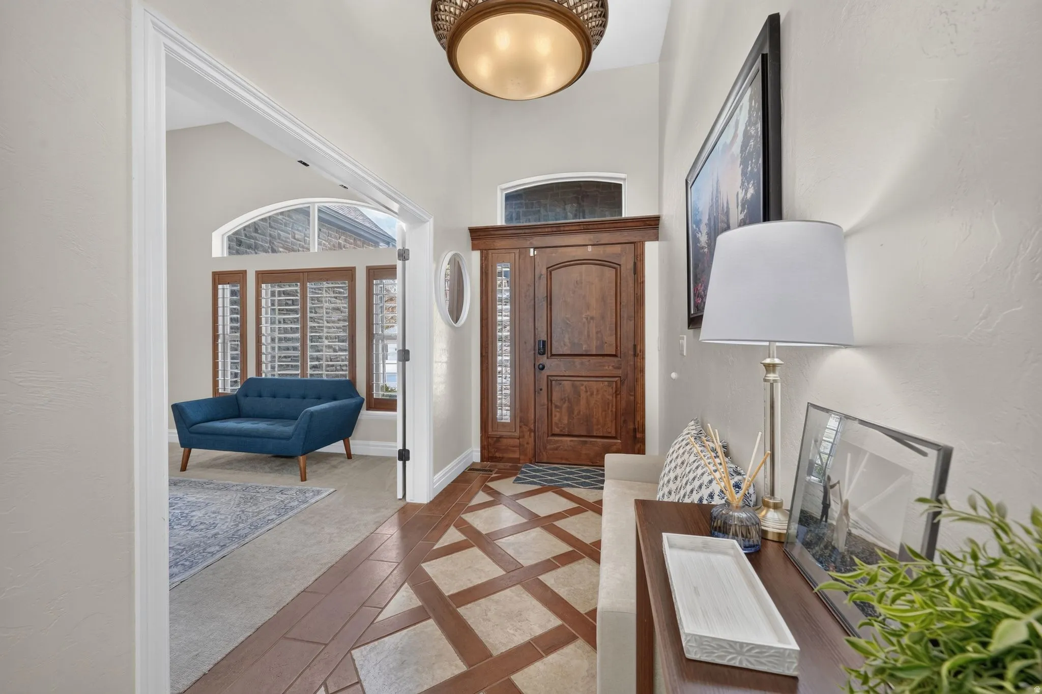 Grand entry featuring a custom wood door with sidelights, decorative ceiling fixture, and patterned tile flooring