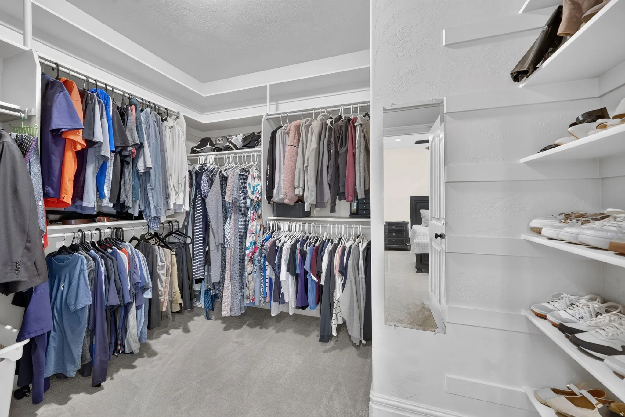 Walk-in closet featuring extensive built-in shelving, multiple hanging rods, and an integrated full-length mirror
