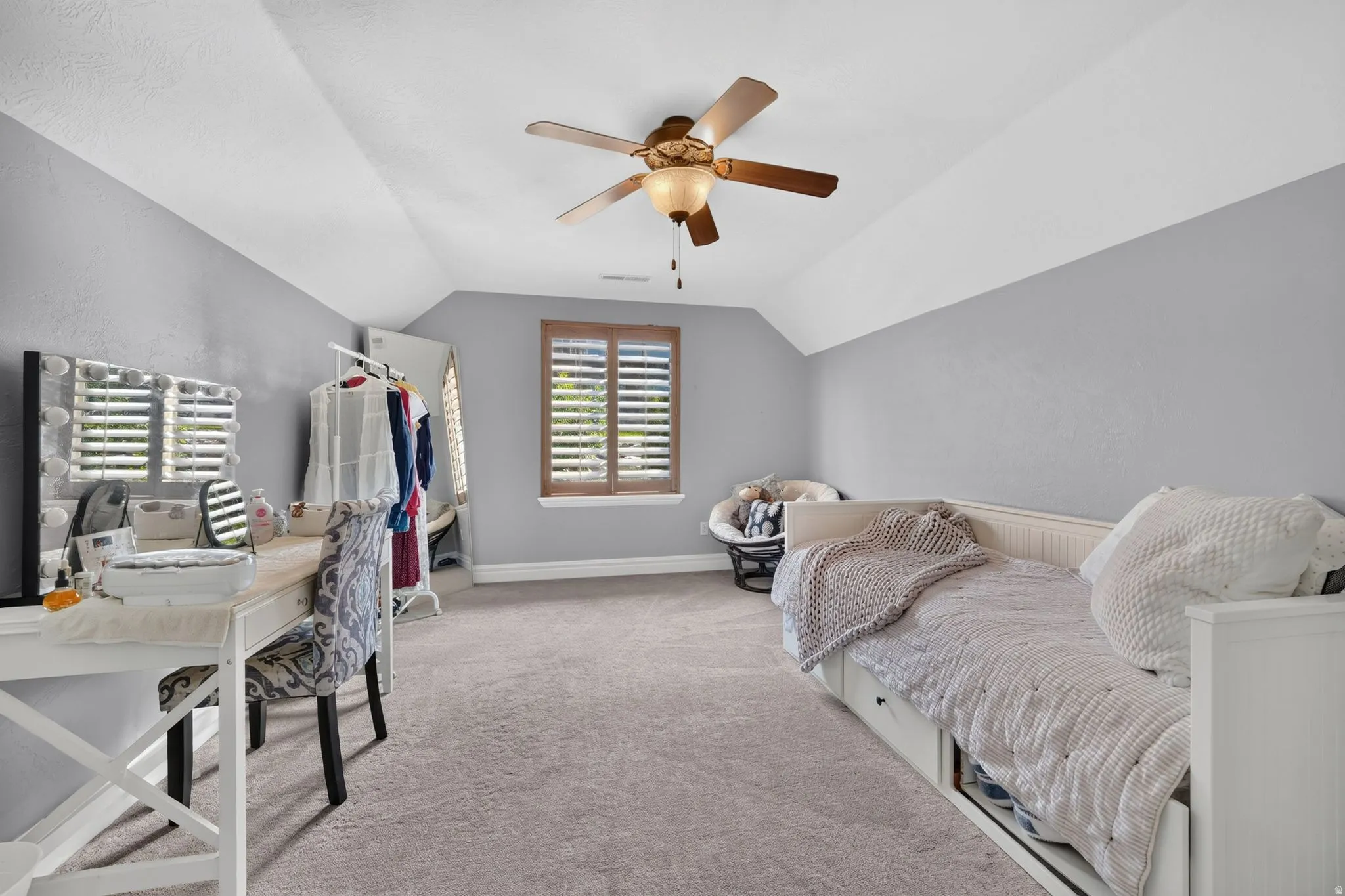 Vaulted ceiling, ceiling fan, wood-finish window shutters, window, and wall-to-wall carpeting